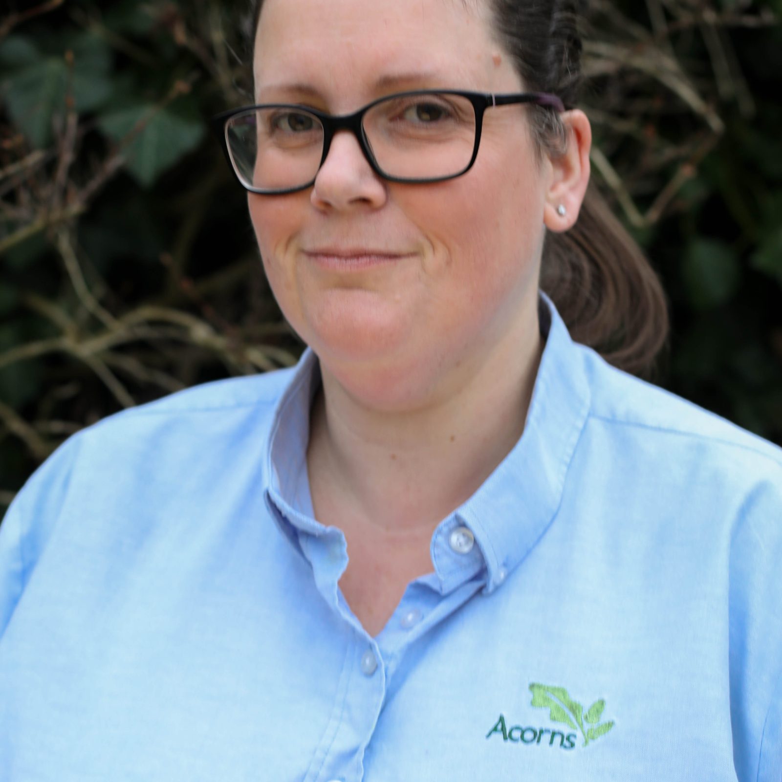 Acorns Nurseries A person wearing glasses and a light blue 